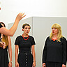 Das Bild zeigt Mitglieder des 4x4-Frauenchors beim Singen. Dabei werden sie angeleitet von Heike Kiefner-Jesatko.