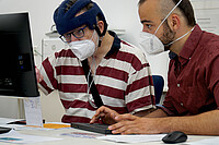 Auf dem Bild sieht man links Hartmut Kabelitz und links Marlon Colbert. Kabelitz zeigt auf einen PC-Bildschirm, Colbert tippt auf der Tastatur. Beide tragen einen Mund-Nase-Schutz. Das Bild wurde in den Büroräumen des AW-ZIB aufgenommen. Copyright: PH Heidelberg