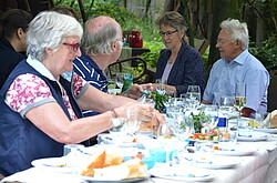 Das Foto zeigt Senioren an einem Tisch im Ökogarten.