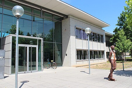 Eingang des Gebäudes zur Pädagogischen Hochschule Heidelberg Abt. Sportwissenschaft/Sportpädagogik. Vor dem Gebäude steht eine Skulptur in Form einer Inline-Skaterin