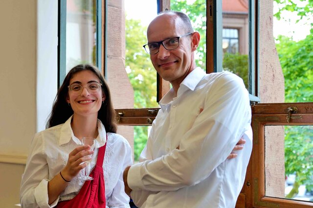 Zu sehen sind zwei Gäste (Frau links, Mann rechts) beim Sektempfang.