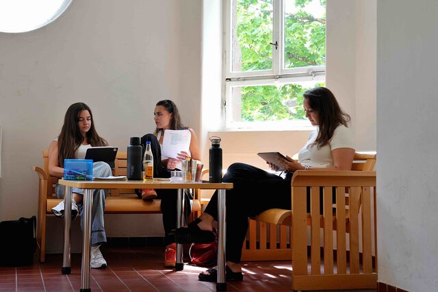 Personn sitzen auf einer Bank im Altbau der PH Heidelberg