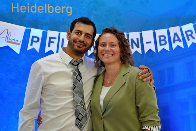 Zu sehen sind ein Mann und eine Frau, die nebeneinander vor einer blauen PHHD-Messewand stehen. An der Wand hängt eine Wimpelkette mit dem Schriftzug „Pflanzenbar“.