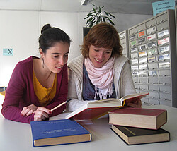  zwei Studentinnen die sich zusammen Bücher anschauen.