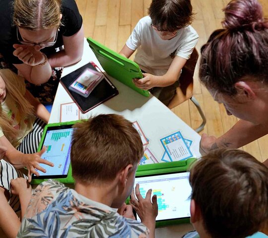zu sehen sind Studierende und Schüler:innen beim Programmieren