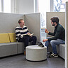 Zwei junge Männer sitzen sich gegenüber und unterhalten sich. Das Bild wurde im Transferzentrum der Hochschule aufgenommen.
