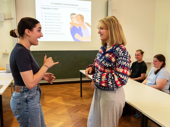 Das Bild zeigt zwei Frauen, die sich in Gebärdensprache unterhalten