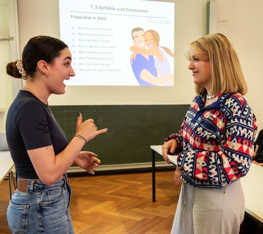 Das Bild zeigt zwei Frauen, die sich in Gebärdensprache unterhalten