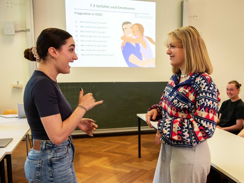 Das Bild zeigt zwei Frauen, die sich in Gebärdensprache unterhalten