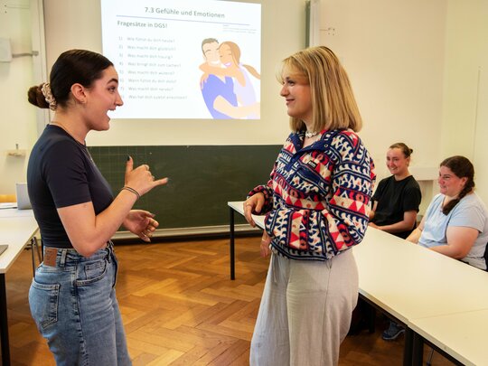 Das Bild zeigt zwei Frauen, die sich in Gebärdensprache unterhalten