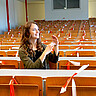 Das Bild zeigt eine Studentin. Sie sitzt alleine in einem Hörsaal und gebärdet mit den Händen. Das Foto wurde an der PH Heidelberg während der Corona-Pandemie aufgenommen; einzelne Sitze sind daher mit Absperrband abgesperrt. Copyright: PH Heidelberg