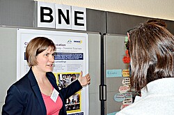 Frau von „TRANSFER TOGETHER“ vor Plakaten.