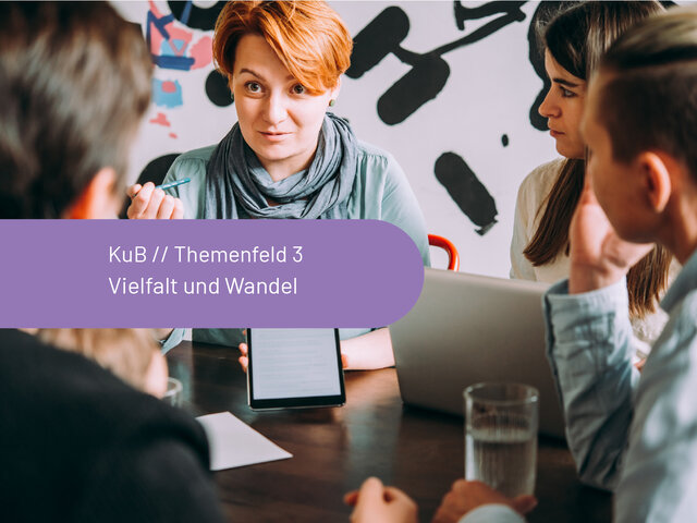 Nahaufnahme von Kleingruppe um einen Tisch mit Laptop und Tablet im Gespräch.