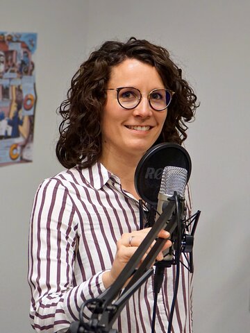 Zu sehen ist Christina Mechler am Mikrofon im Podcast-Studio.