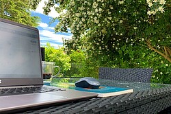 Das Bild zeigt einen Computer auf einem Tisch im Garten.