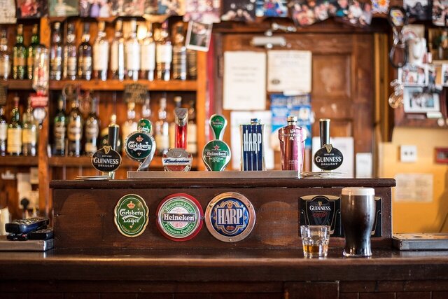 Irish Pub mit Blick auf die Zapfhähne. Im Hintergrund stehen noch weitere Flaschen in einem Regal.