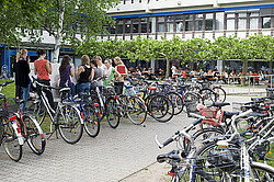 Studierende an den Fahrradständern vor dem Neubau der Hochschule.