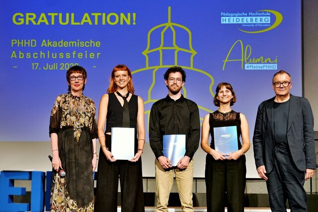 Zu sehen sind Absolvent:innen der PHHD, die sich mit ihren Urkundenmappen auf der Bühne zum Gruppenfoto aufgestellt haben.