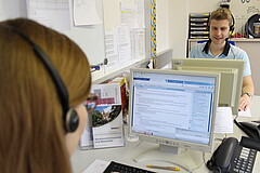 Auf dem Symbolbild sind zwei Mitarbeiter:innen der Telefonhotline zu sehen.