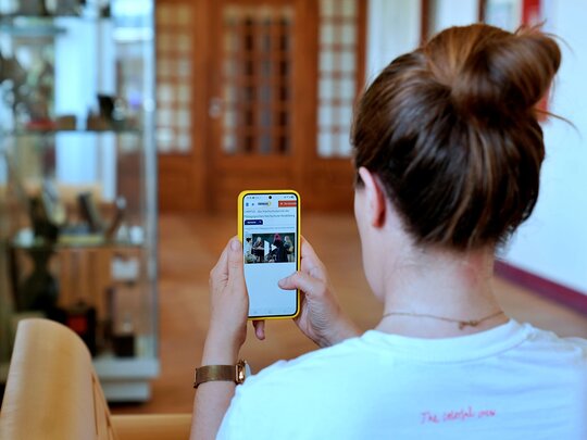 Frau hält Handy auf dem man das Campus-Portal der Pädagogischen Hochschule Heidelberg sieht