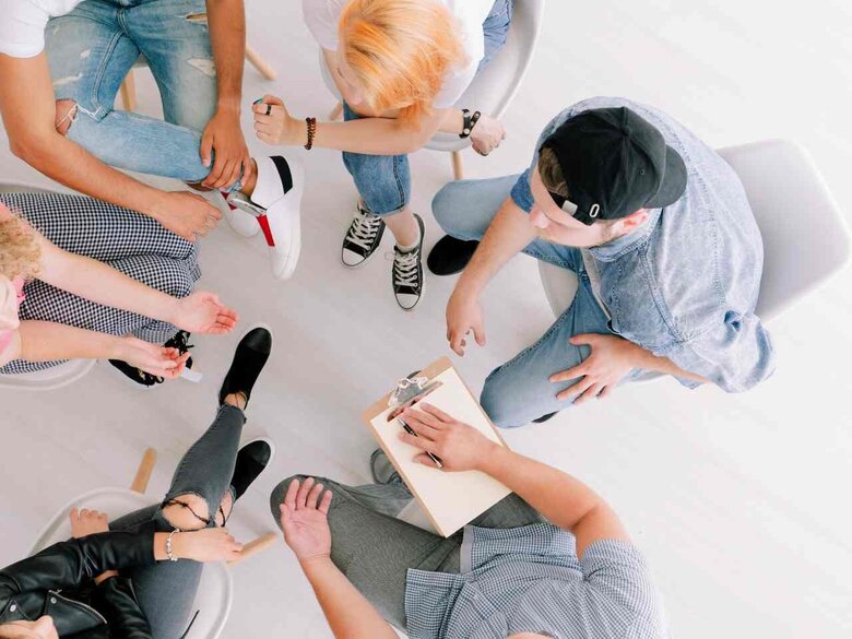 Eine Gruppen sitzt im Stuhlkreis. Das Foto ist von oben aufgenommen, sodass man keine Gesichter erkennt. 