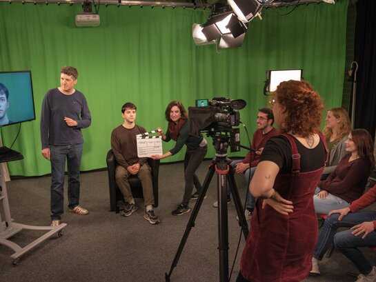 Mehrere Studenten machen eine Aufnahme mit Videokamera im Fernsehstudio