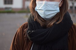  Frau mit einer medizinischen Maske auf dem Innenhof der PH