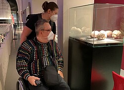 Das Bild zeigt zwei Mitarbeiter:innen von dem Projekt KuLo in einem Museum. Ein Mitarbeiter sitzt im Rollstuhl. Copyright Pädagogische Hochschule Heidelberg