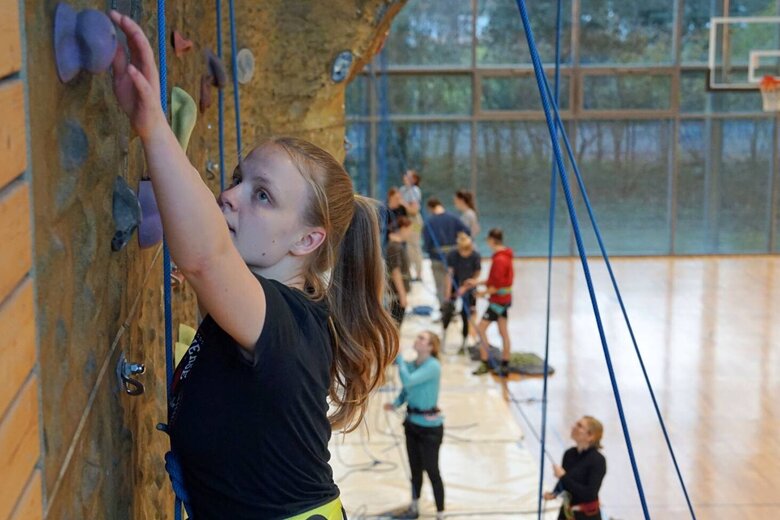 Nahaufname einer Studentin an der Kletterwand in der Sporthalle.