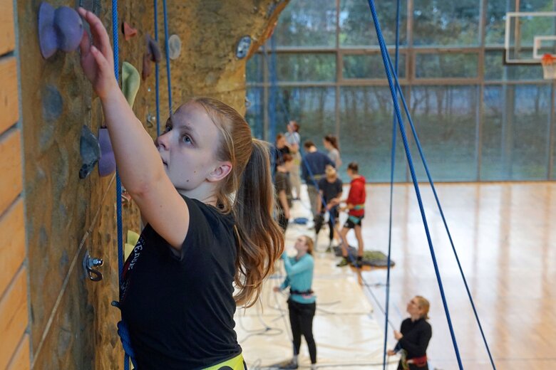 Nahaufname einer Studentin an der Kletterwand in der Sporthalle.