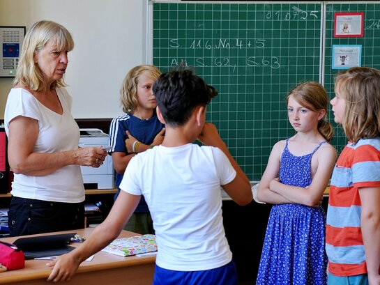 Das Foto zeigt eine Lehrkraft im Gespräch mit Schüler:innen.