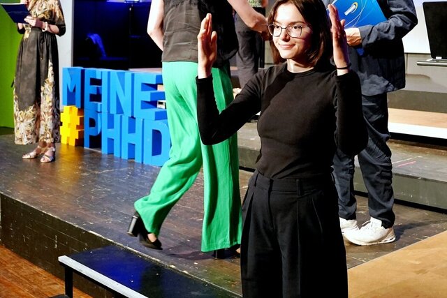 Zu sehen sind Absolvent:innen, die zur Ehrung auf die Bühne gehen.