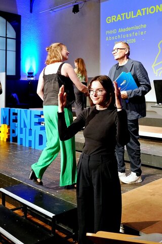 Zu sehen sind Absolvent:innen, die zur Ehrung auf die Bühne gehen.