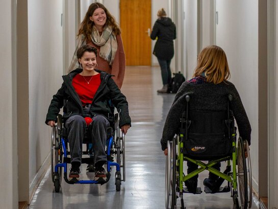 Das Bild zeigt Studierende, die am Tag der Vielfalt ausprobieren, sich mit einem Rollstuhl im Altbau der PH Heidelberg fortzubewegen.