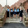 Auf dem Bild sieht man die vier Preisträgerinnen gemeinsam mit Vera Heyl. Sie stehen auf der Treppen, die vom Innenhof in den Altbau führt. Die Preisträgerinnen halten ihre Urkunden sowie Blumen in der Hand. Copyright: PH Heidelberg