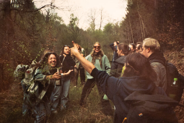 Teilnehmende der Musik-Hütte stehen in einem lockeren Kreis im Wald und tanzen gut gelaunt.