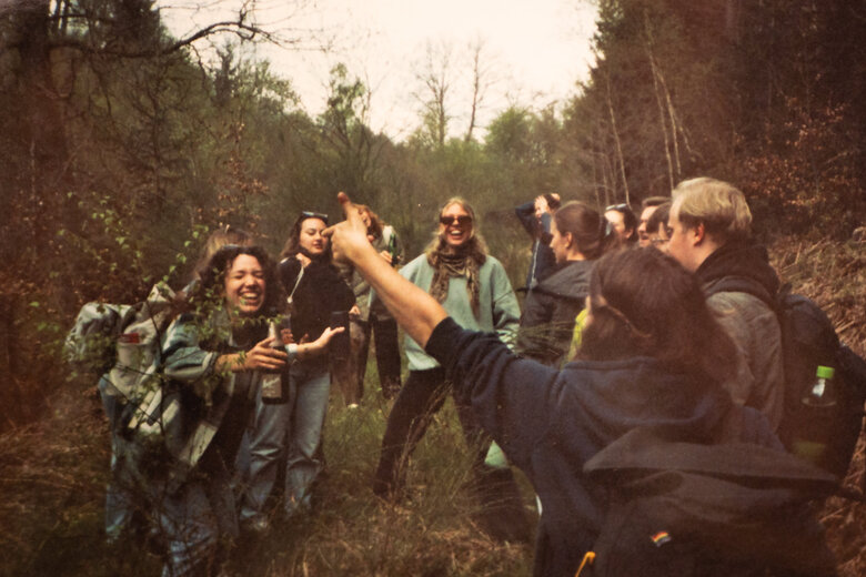 Teilnehmende der Musik-Hütte stehen in einem lockeren Kreis im Wald und tanzen gut gelaunt.