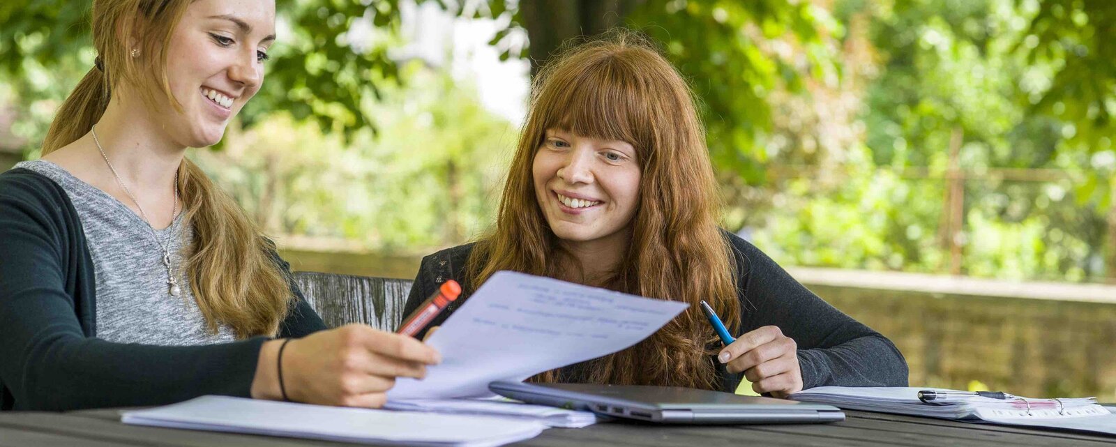 Zwei Studentinnen der Pädagogischen Hochschule sitzen im Innenhof des Altbaus auf Mobiliar, das PHeelGood mitgestaltet hat und so gesundes Studieren ermöglicht.