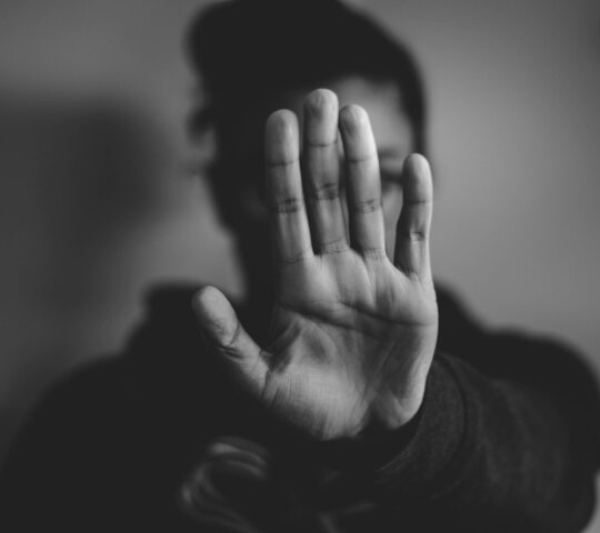 Eine Person gibt ein Stoppzeichen mit der Hand.