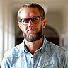 Die Porträtaufnahme zeigt Christian Heuer. Er steht im Altbauflur der Hochschule. 