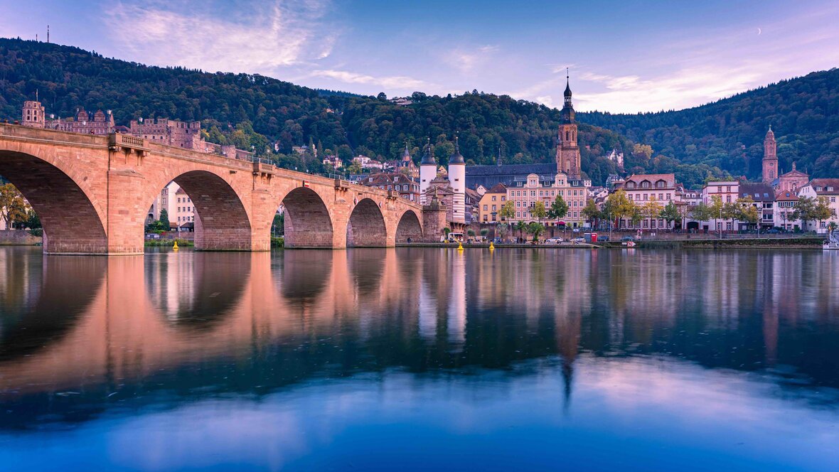 Zu Leben in Heidelberg bedeutet auch schöne Abendsommer an der Heidelberger Altstadtbrücke zu verbringen, so wie man es auf diesem Bild sieht.