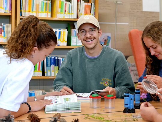 Zu sehen ist ein Student, der in die Kamera lächelt.