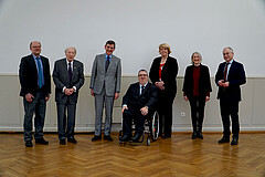 Das Bild zeigt die Personen, die bei der Nachqualifizierung gesprochen haben. Sie stehen neben einander. Das Foto wurde in der Aula der Hochschule aufgenommen. 