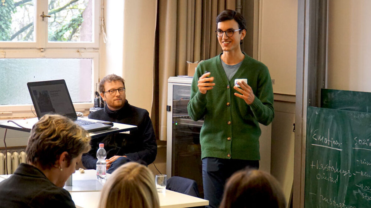 Ein junger Mann, der an der PHHD arbeitet, präsentiert in einem Seminarraum seine Arbeit.