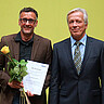 Michael Neuberger und Karl-Heinz Dammer. Neuberger hat die Lehrpreis-Urkunde und eine gelbe Rose in der Hand. Beide schauen freundlich in die Kamera.
