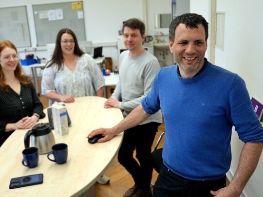 Mitarbeitende der Stabstelle Qualitätsmanagment (SQM) arbeiten zusammen an einem Stehtisch.