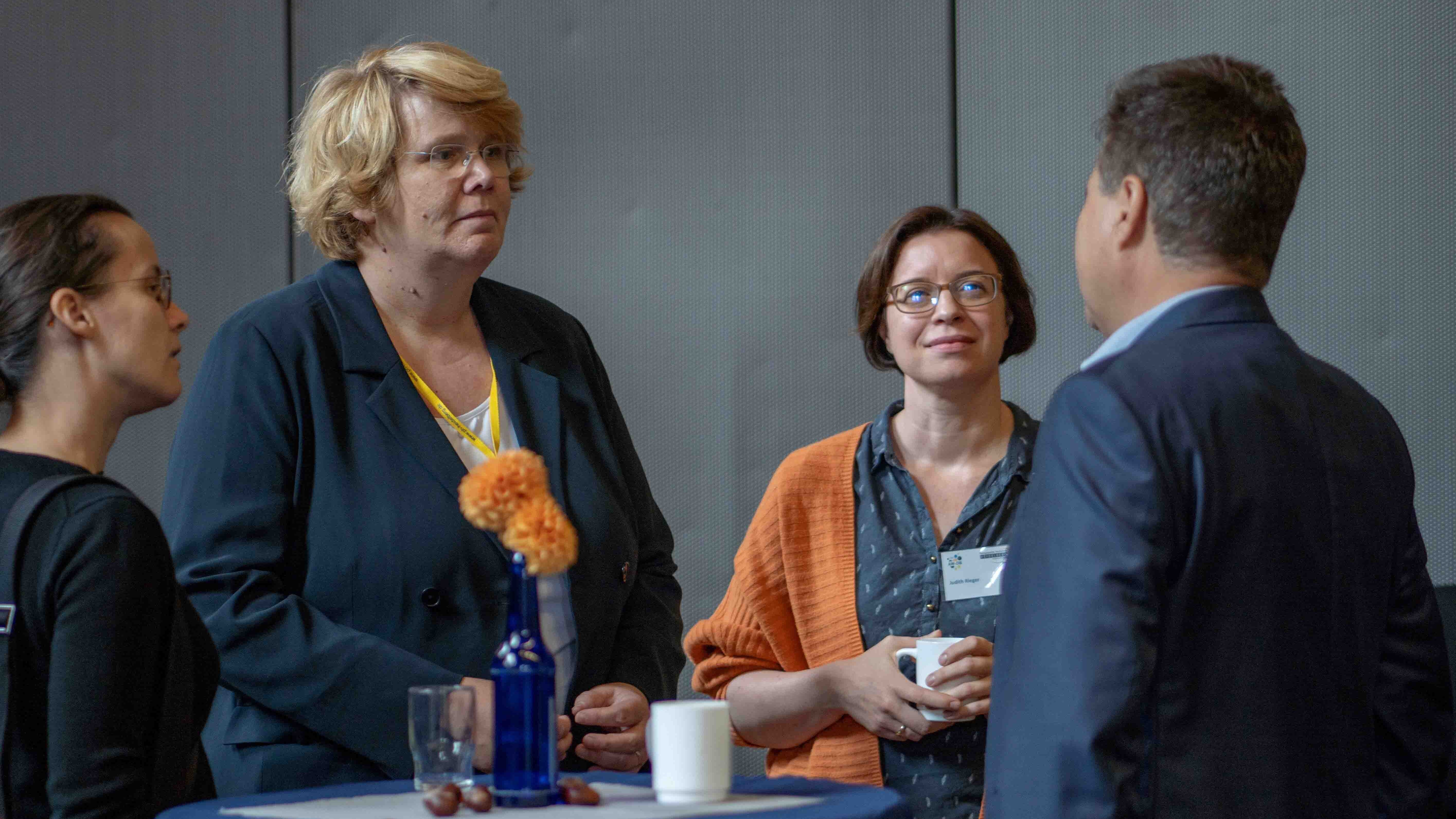 Das Bild zeigt Prof. Dr. Karin Terfloth im Gespräch mit Judith Rieger, Jürgen Dusel und anderen an einem Stehtisch.
