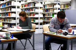 Das Bild zeigt zwei Studierende beim lernen in der Bibliothek.