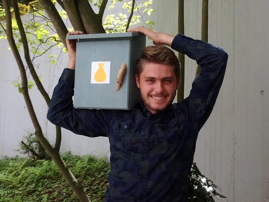 Das Bild zeigt Fabian Braun, der eine Kiste auf seinen Schultern trägt.