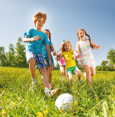  Kinder die auf einer Wiese Fußball spielen.